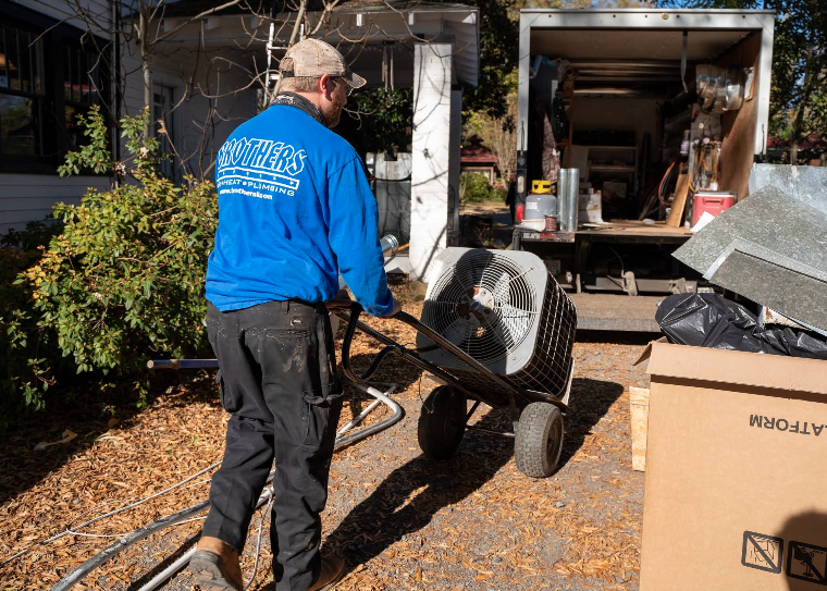 Brothers technician wheeling an outdoor AC unit from a service truck for emergency AC service in Charlotte.