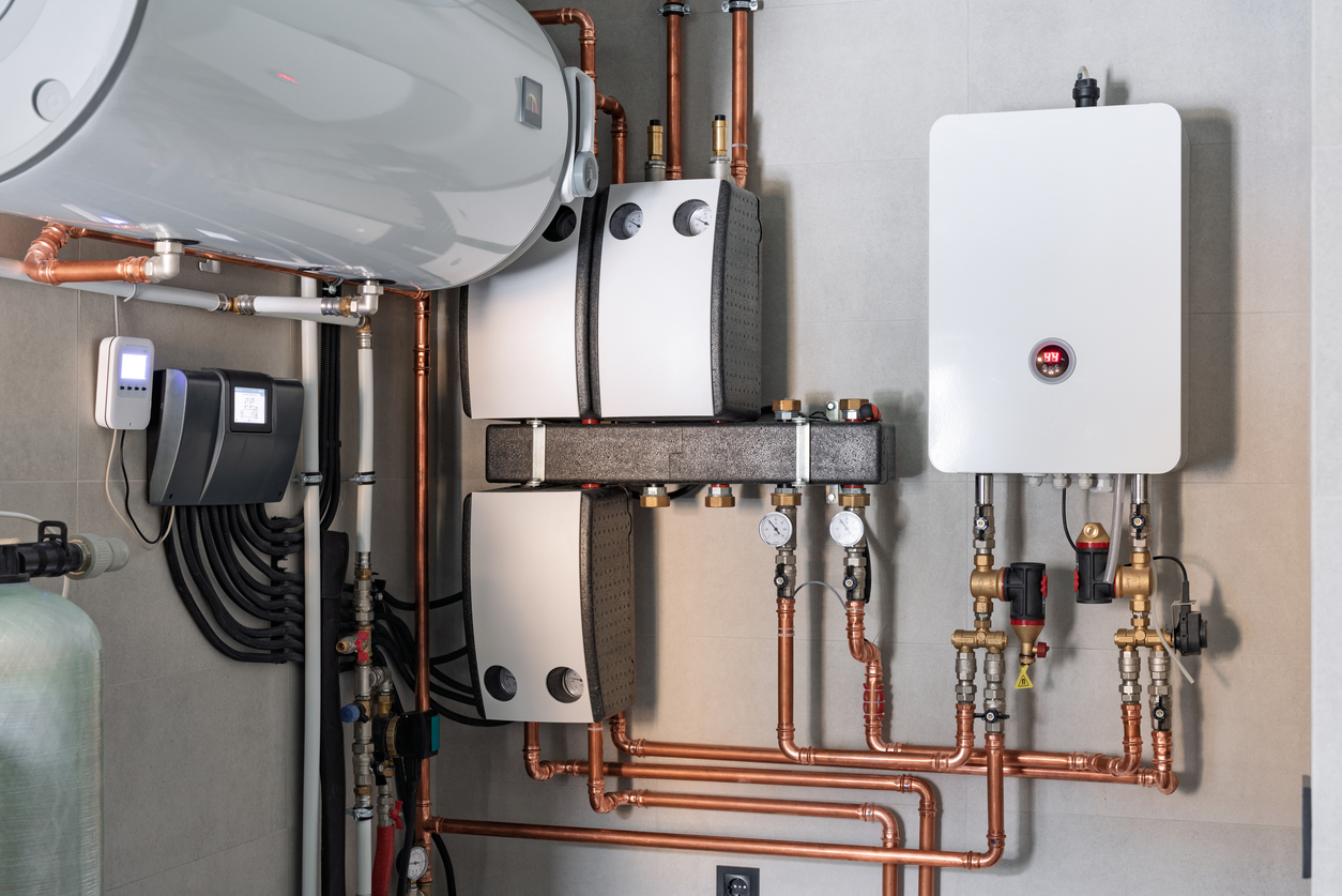 Wall installation of electric boiler device, valves, pumps, copper tubing, water heater, and automatic controller in a single-family home.