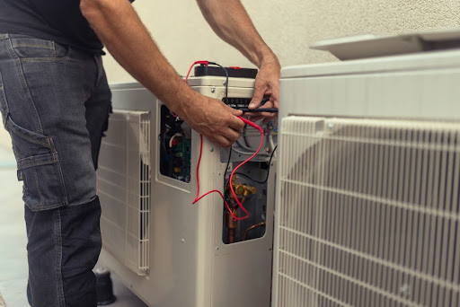 Close-up on the hands of the electrician installing the heat pump, connecting the wires.