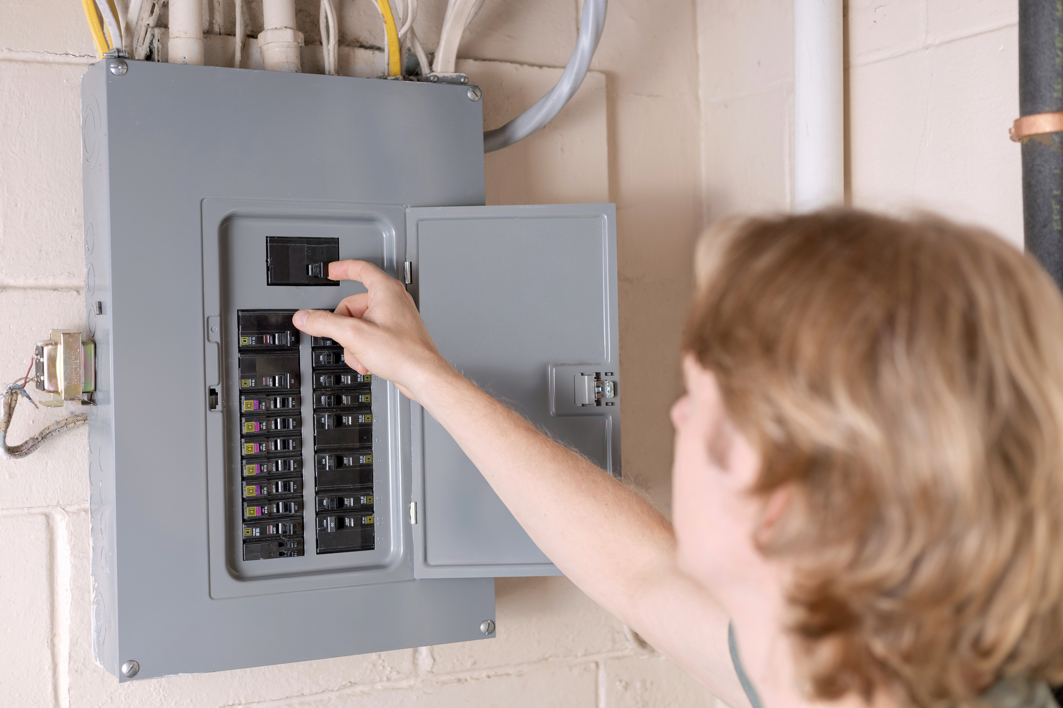 A man resetting a circuit breaker by flipping the switches.