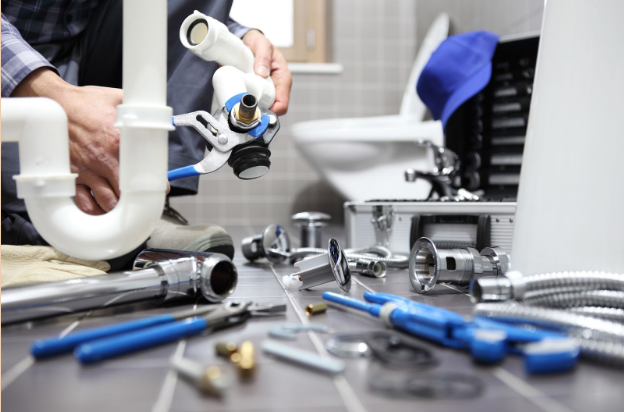 A man inspects plumbing components on the bathroom floor.