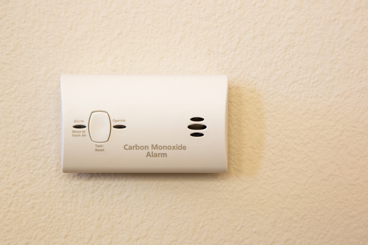 Wall-mounted carbon monoxide alarm for leaks detected in an HVAC emergency.