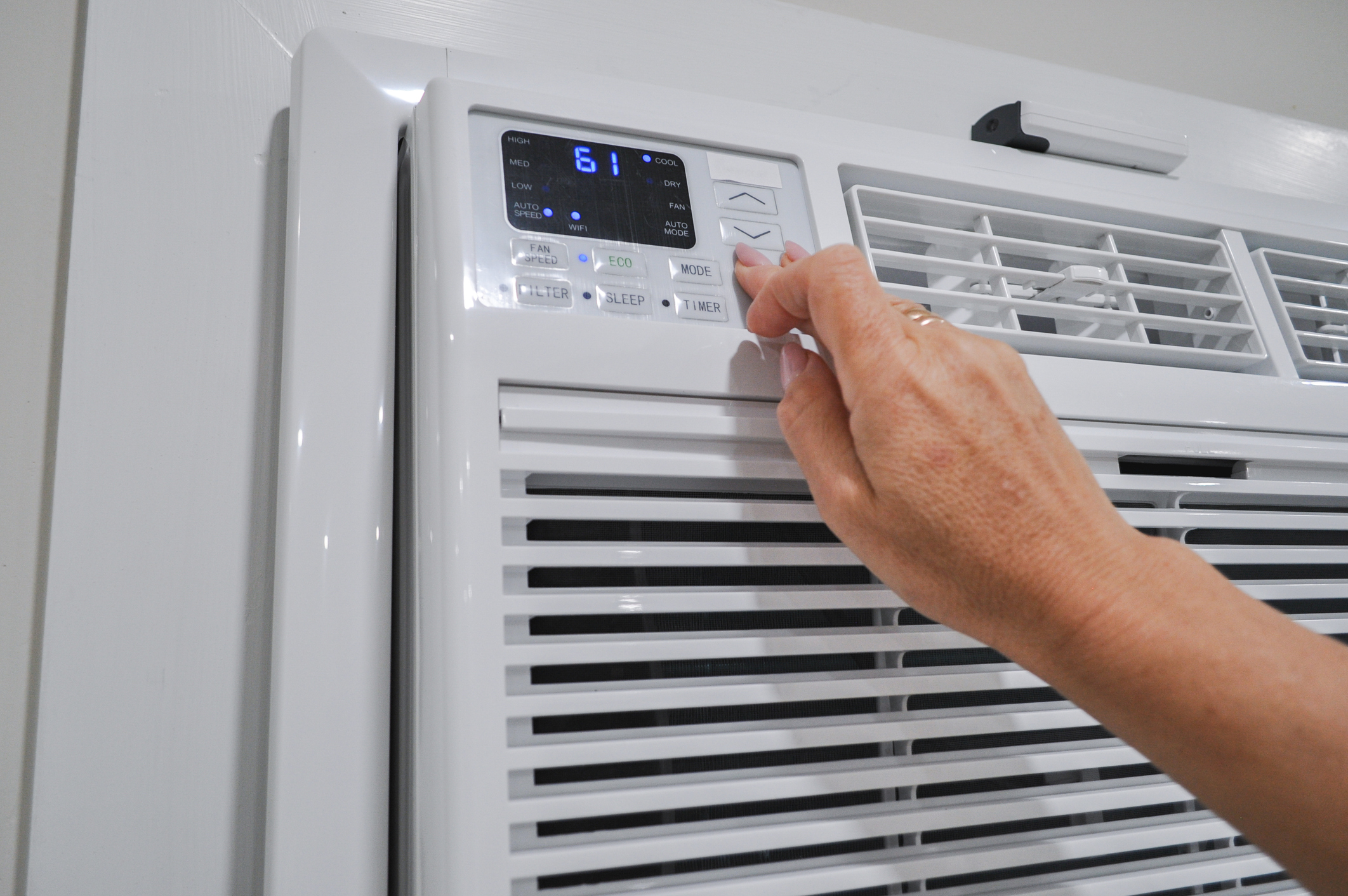 Hand pressing buttons on a cooling appliance for controlling indoor climate