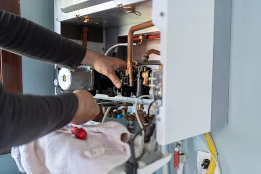 Brothers technician repairing natural gas combi boiler at residential home.